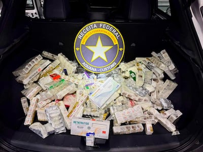 Paquetes de medicamentos apilados en el maletero de un vehículo, con distintivo de la Receita Federal de Brasil.