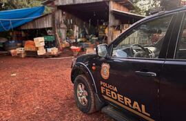 Vehículo de la Policía Federal con logotipo visible, estacionado junto a un galpón de madera en un entorno rural.