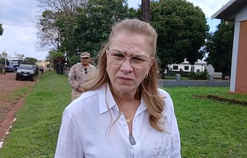 María Teresa Barán con cabello largo y rubio, vista en primer plano, mientras un hombre en segundo plano observa con atención.