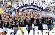 Rodrigo Nogués Coto y Richard Ortiz celebran con el trofeo, rodeados de aficionados en camisetas negras del Club Olimpia.