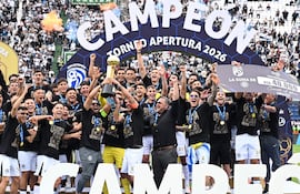 Rodrigo Nogués Coto y Richard Ortiz celebran con el trofeo, rodeados de aficionados en camisetas negras del Club Olimpia.