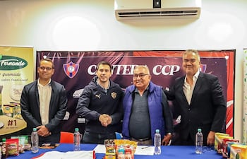 Cuatro hombres en mesa; uno en chaqueta negra, otro con chaleco azul y gafas, celebrando un acuerdo entre Cerro Porteño y Arco Iris.
