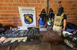 Un uniformado custodia a los aprehendidos Roque Garcete y Edemar Ramírez con las evidencias encontradas en su poder, en la comunidad de Carmelo Peralta.