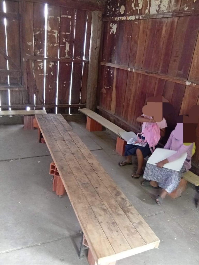 Niñas dan clases en improvisados bancos, casi en el suelo, ante la falta de sillas, mesas o pupitres en una escuela indígena de Puerto Pinasco.