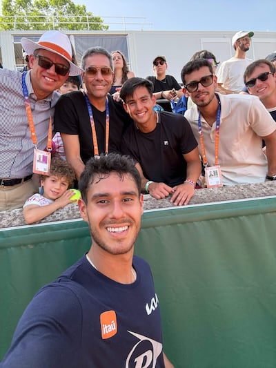 Daniel Vallejo sonríe con gafas de sol, rodeado de amigos sonrientes en un evento deportivo al aire libre.