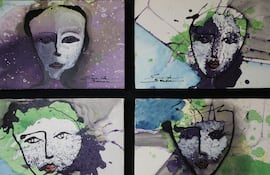 Cuatro cuadros con retratos abstractos de rostros humanos en la galería. Colores predominantes: púrpura, verde, azul y negro.