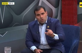 Manuel Achucarro Gill, vestido con traje azul y camisa blanca, discute en un moderno estudio de televisión.