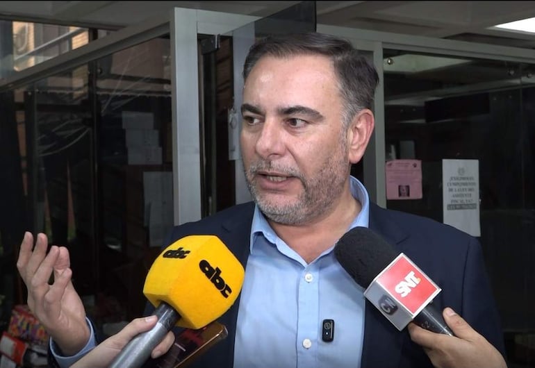 El senador Ever Villalba, con camisa azul y saco oscuro, gesticula mientras habla a reporteros en un ambiente urbano.