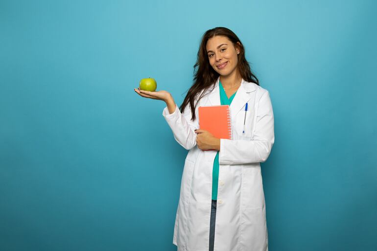 Nutricionista sostiene un cuaderno y una manzana.
