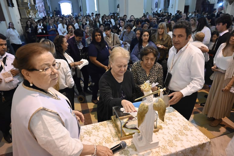 Mujeres en la Catedral Metropolitana, una viste atuendo blanco y gafas, acompañadas por otras dos, en un ambiente solemne.