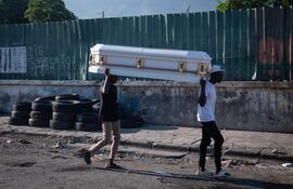 Dos hombres cargan un ataúd por una calleen Puerto Príncipe (Haití). Presuntos delincuentes fueron abatidos por la Policía Nacional de Haití durante un ataque al Palacio Nacional el fin de semana en Puerto Príncipe, orquestado por la coalición de bandas armadas "Vivre Ensemble", según publicaron este sábado medios locales. EFE/ Johnson Sabin