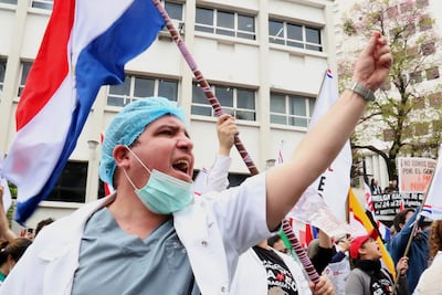 Un médico participa en una protesta este lunes, en Asunción (Paraguay). Médicos del sector público marcharon y protagonizaron concentraciones en Paraguay, en el primer día de una huelga general que han convocado hasta el viernes para exigir un reajuste salarial, mejores condiciones laborales y la dotación de insumos y medicamentos en los hospitales. EFE/ Nina Osorio