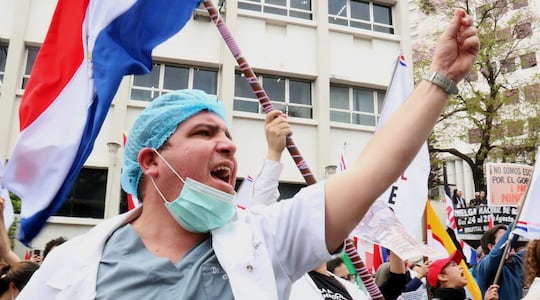 Un médico participa en una protesta este lunes, en Asunción (Paraguay). Médicos del sector público marcharon y protagonizaron concentraciones en Paraguay, en el primer día de una huelga general que han convocado hasta el viernes para exigir un reajuste salarial, mejores condiciones laborales y la dotación de insumos y medicamentos en los hospitales. EFE/ Nina Osorio