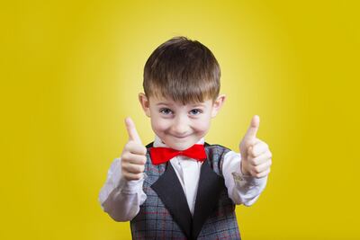 Un niño hace la señal de ok con ambas manos.