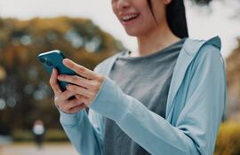 Mujer con las manos en un celular, concepto de uso de apps.