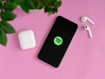 Un teléfono celular conectado a Spotify con dos auriculares