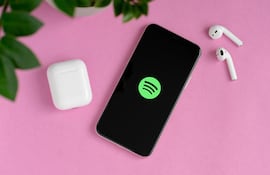 Un teléfono celular conectado a Spotify con dos auriculares