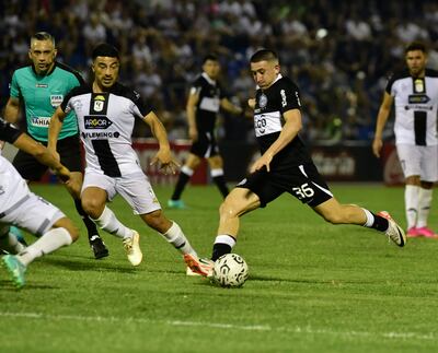 Facundo Zabala se alista para sacar un remate ante la mirada del volante de Tacuary Nelson Acevedo.