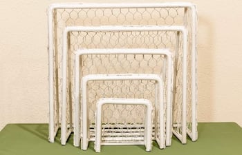 Varios arcos de fútbol en diferentes tamaños, dispuestos sobre una superficie verde en un ambiente interior.