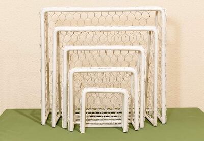 Varios arcos de fútbol en diferentes tamaños, dispuestos sobre una superficie verde en un ambiente interior.