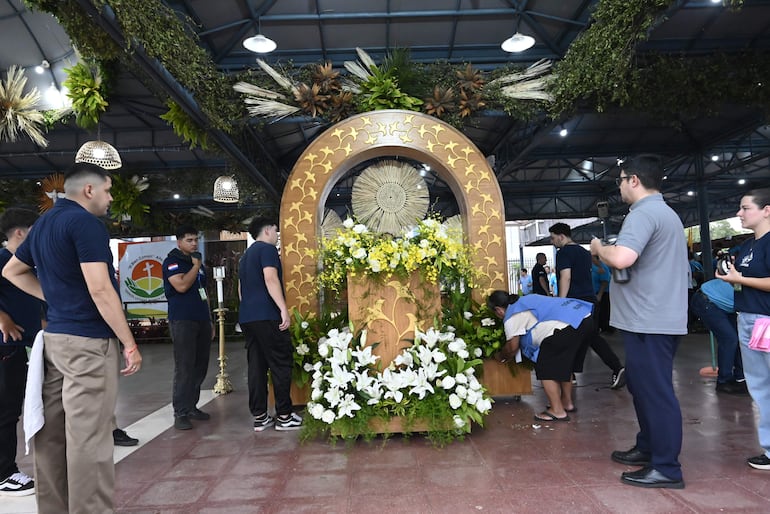 El pedestal de la imagen de la Virgen de Caacupé está adornado con flores blancas y amarillas. 