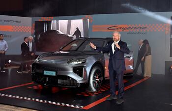 Miguel Carrizosa en traje oscuro presenta el Porsche Cayenne eléctrico, rodeado de una audiencia interesante en un salón decorado.