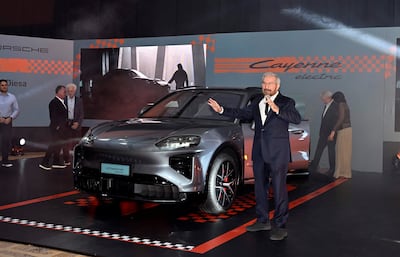 Miguel Carrizosa en traje oscuro presenta el Porsche Cayenne eléctrico, rodeado de una audiencia interesante en un salón decorado.