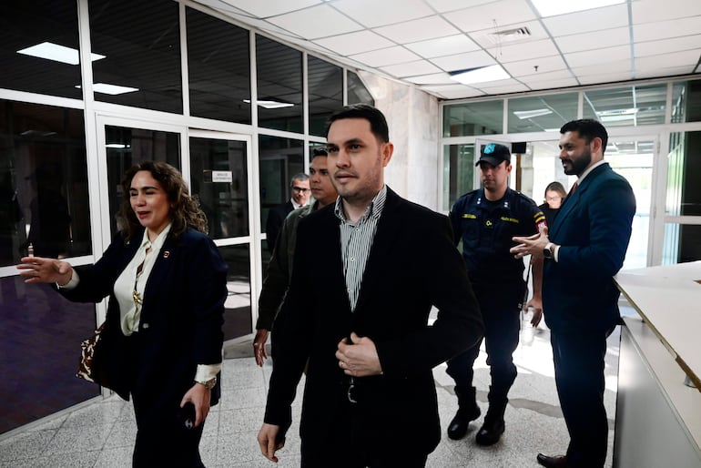 Alba Zaracho con chaqueta oscura y Hernán Rivas Roman con camisa a rayas conversan en un ambiente de oficina claro y amplio.