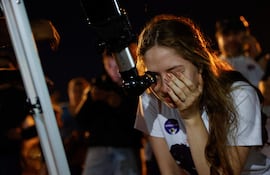 Una mujer observa por un telescopio el eclipse lunar parcial este martes, en Asunción (Paraguay).