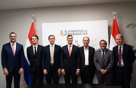 Santiago Peña, Xavier Niel y otros hombres en traje posan sonrientes frente al logotipo del Gobierno del Paraguay.