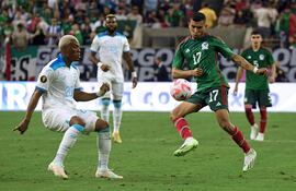 El mexicano Orbelín Pineda (d) lucha por la posesión del balón con el hondureño Deybi Flores, durante el partido que ganaron los aztecas por 4-0.