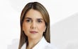 María Gloria Rodríguez de pie, con camisa blanca y pantalón negro, presenta postura erguida en un entorno urbano moderno.