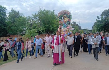 Monseñor Gabriel Escobar con túnica rosa lleva un bastón y es seguido por un grupo de aproximadamente 30 personas en una marcha religiosa.