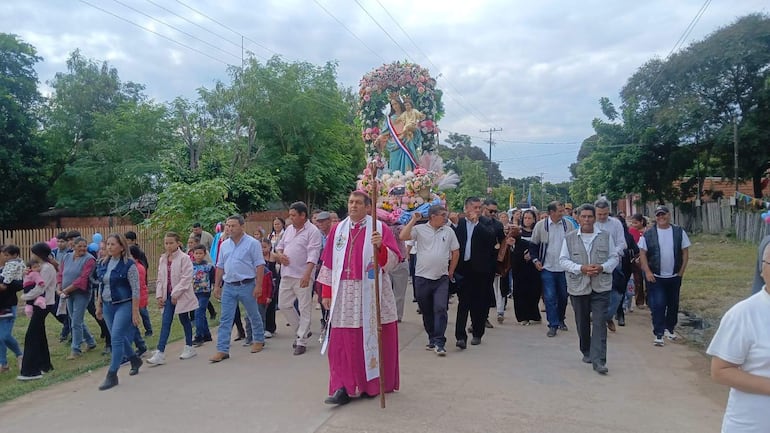 Monseñor Gabriel Escobar con túnica rosa lleva un bastón y es seguido por un grupo de aproximadamente 30 personas en una marcha religiosa.