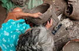 Una maestra artesana trabaja con el ñai’û (barro negro) para dar forma a distintos elementos.