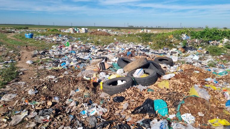 Basural en Villa Florida, con montañas de residuos plásticos y neumáticos en un área rural, sin personas presentes.