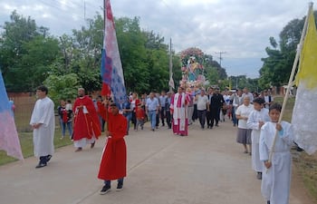 Tres figuras con túnicas religiosas, una en manto rojo, marchan con estandarte en celebración, con un entorno residencial y árboles.