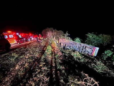 Autobús volcado en el centro de la escena, rodeado de ambulancias y rescatistas en la oscuridad de la noche.