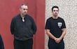 Fernando Barrionuevo en camisa y pantalón negro, Aitor Barrionuevo en camiseta negra, ambos con expresión seria en un entorno interior rojo.
