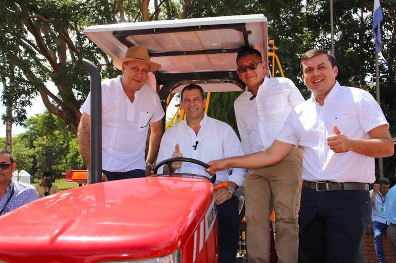 El ministro de Agricultura Carlos Giménez posa al mando de un tractor en la Escuela Agrícola de San Pedro, rodeado por otros funcionarios.
