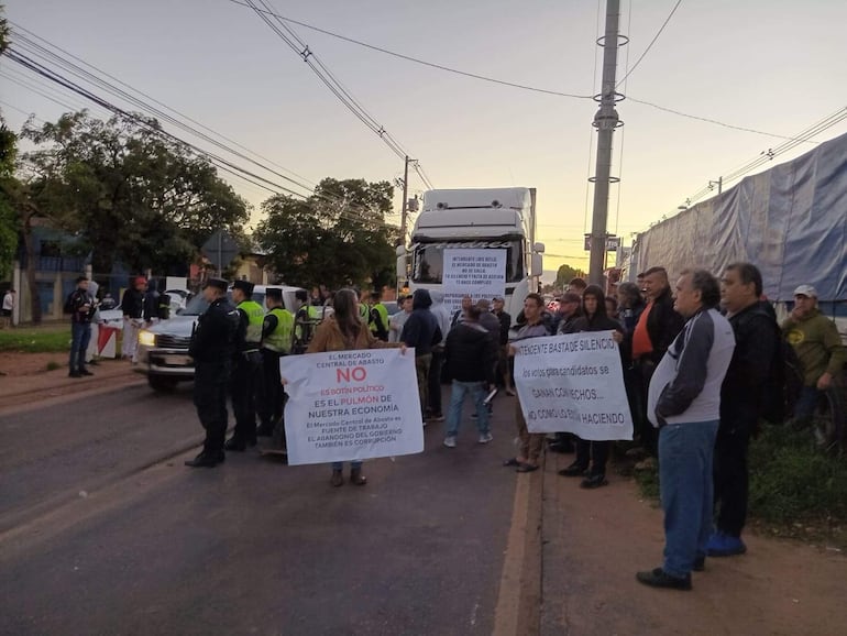 Grupo de manifestantes sosteniendo pancartas sobre el Mercado de Abasto, con policías y vehículos en el fondo.