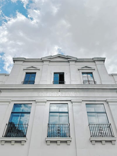 Fachada del Edificio Staudt, blanco con detalles arquitectónicos, molduras y balcones, bajo un cielo parcialmente nublado.
