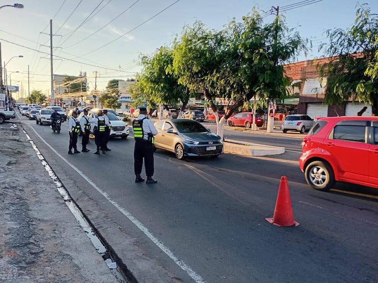 Agentes de tránsito con chalecos verdes dirigen el tráfico junto a un camión varado, mientras conductores observan la situación.