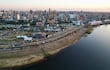Vista aérea de Asunción al atardecer, con edificios destacando y el río visible en el primer plano.