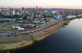 Vista aérea de Asunción al atardecer, con edificios destacando y el río visible en el primer plano.