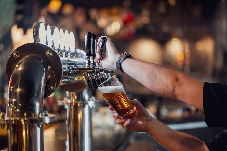 Un bartender sirve un vaso de cerveza.