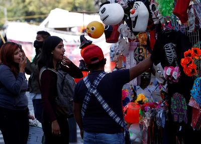 Grupos de personas observan un puesto ambulante con máscaras de Halloween, el 26 de octubre de 2021, en la Ciudad de México (México). A pesar de que México está fuertemente influenciado por la cultura estadounidense, la tradicional festividad del Día de Muertos ha resistido y coexistido junto a la celebración de Halloween en un sincretismo, tal vez, único en el mundo. EFE/ Mario Guzmán