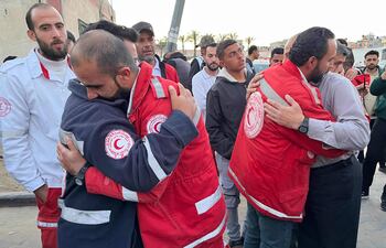 Empleados de la Media Luna Roja Palestina se abrazan mientras trasladan los cuerpos de sus compañeros a Jan Yunis, en el sur de Gaza