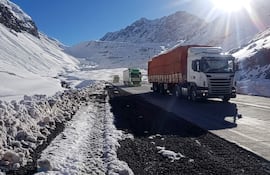 Tres camiones en carretera, con montañas nevadas y un cielo despejado de fondo, crean una escena visual impactante.