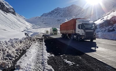 Tres camiones en carretera, con montañas nevadas y un cielo despejado de fondo, crean una escena visual impactante.